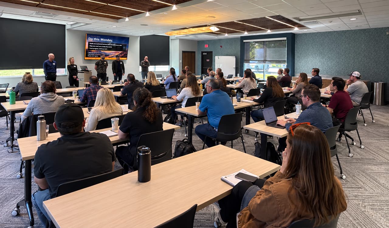 Participants seated at tables with laptops, facing presenters in the Lab room.